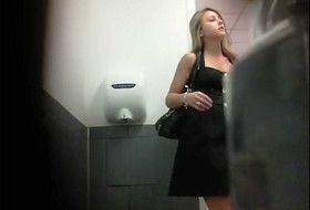 A girl in a black dress poops in front of the camera in the toilet